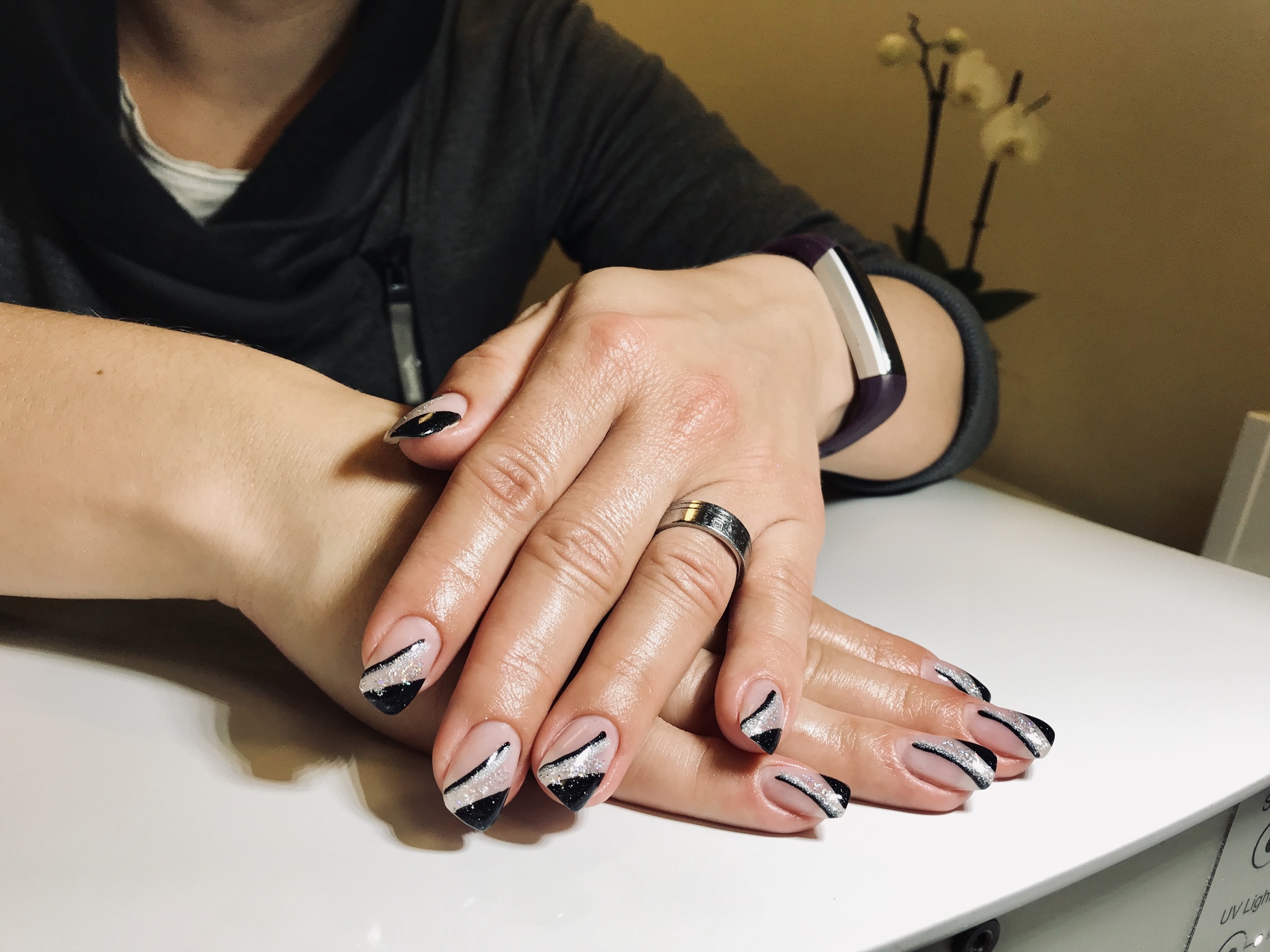 Foto von Händen einer Frau mit  langen schwarz, silbernen Nägeln