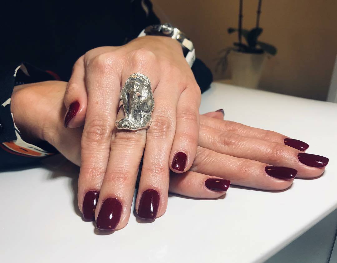 Foto von Händen einer Frau mit dunkelroten Fingernägeln