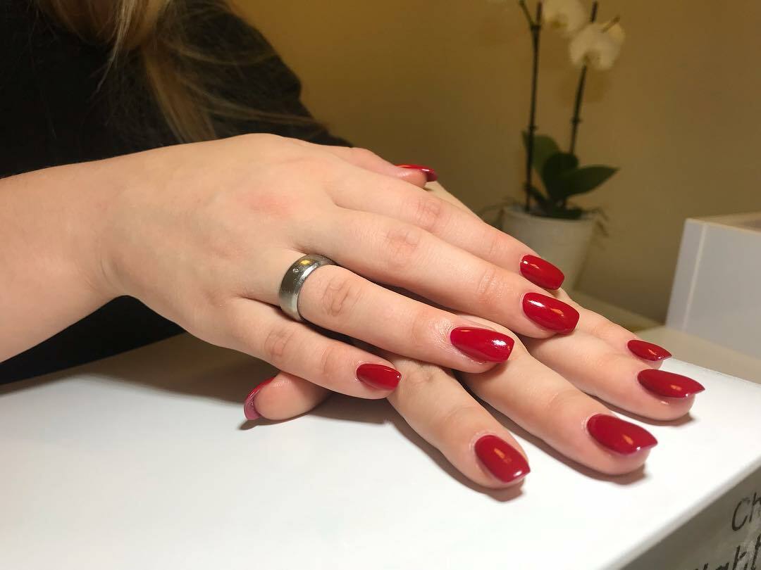 Foto von Händen einer Frau mit langen, roten Nägeln